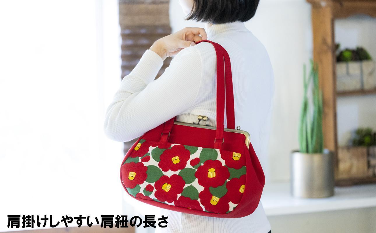 がま口バッグを肩掛けした女性の後ろ姿。肩掛けしやすい肩紐の長さが特徴です。